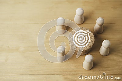 Wooden figure encompass white dartboard and arrow print screen on round wooden block on table for setup business objective target Stock Photo