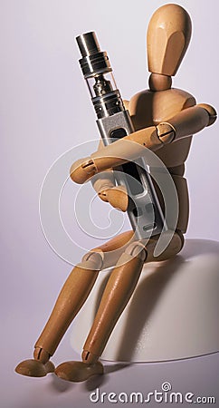 Wooden figure holding an electronic cigarette. Stock Photo