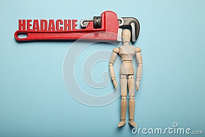 Wooden figure of man with his head clamped in vice with inscription Headache. Pain, stress, migraine Stock Photo