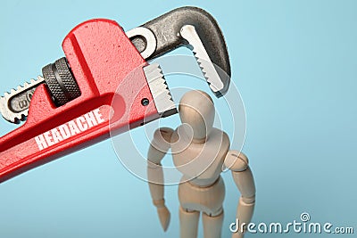 Wooden figure of man with his head clamped in vice with inscription Headache. Pain, stress, migraine Stock Photo