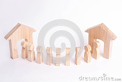 A wooden figure of a man meets a guest on a white background. Wooden house. The concept of an apartment house, real estate. Buying Stock Photo