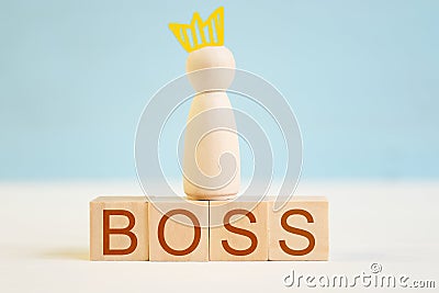 Wooden figure of man with painted crown on toy blocks with inscription boss Stock Photo