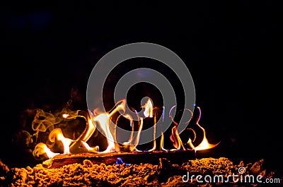 Wooden figures 2018 are burned in a flame. Conceptual photo end of the year. Stock Photo