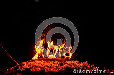 Wooden figures 2018 are burned in a flame. Conceptual photo end of the year. Stock Photo