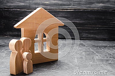 Wooden figures of the family stand near a wooden house. The concept of finding a new home, moving. A healthy strong family Stock Photo