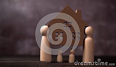 Wooden figures family standing and bear wooden house to Protect and burden the problems to protect the family. The concept of Stock Photo