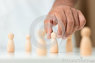 Wooden figures human was chosen leadership of teamwork. man hands are select wooden puppet to devise strategies for appointing Stock Photo