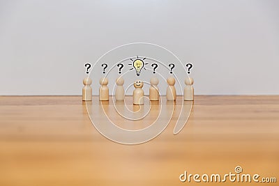 Wooden figures of people confused with question marks and an idea bulb Stock Photo