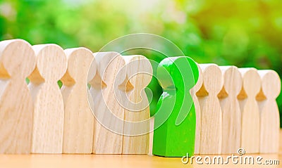 Wooden figures of people. The green man comes out with a team of workers. The concept of choosing a new leader. Choice of person. Stock Photo