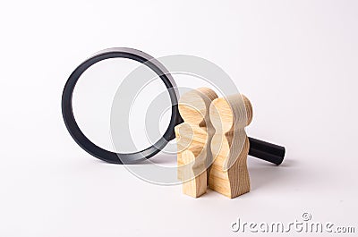 Wooden figures of people stand near the magnifying glass. The family is looking for something. The concept of housing search. Stock Photo
