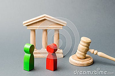 Wooden figures of people standing near the judge`s gavel. Litigation. Business rivals. Conflict of interest. Law and justice. The Stock Photo