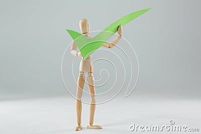 Wooden figurine holding a tick sign Stock Photo