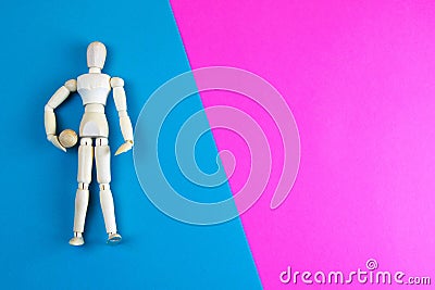 Wooden figurine of a man with a ball on a blue and pink background with clear space for text Stock Photo