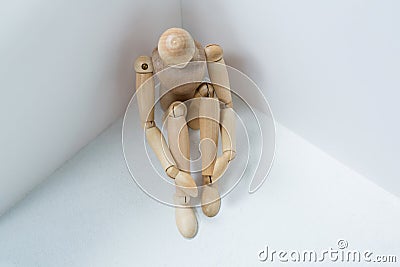 Wooden figurine sitting against wall Stock Photo