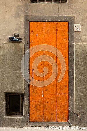 Wooden front door and house number 31 on old wall. Orange door on gray background Stock Photo
