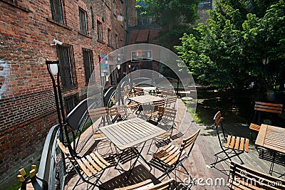 Wooden furniture of outdoor cafe without people at the gothic building Editorial Stock Photo