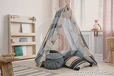Wooden furniture and tent with pillows in natural scandinavian playroom for kids, real photofox Stock Photo