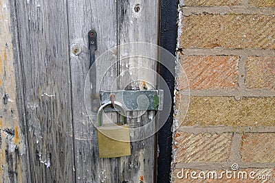 Wooden garage door secured by a brass padlock Editorial Stock Photo