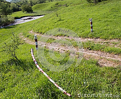 Wooden gate on the road with green grass Stock Photo