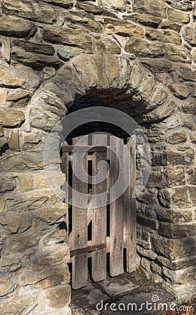 A wooden gate in a stone wall entranceway on a sunny winter day Stock Photo