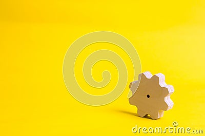 A wooden gear on a yellow background. The concept of technology and business processes. Minimalism. Mechanisms and devices. Work, Stock Photo