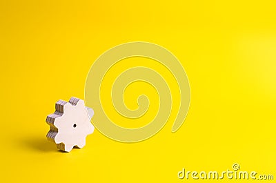 A wooden gear on a yellow background. The concept of technology Stock Photo
