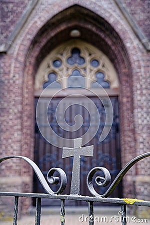 Wooden gothic church door behind an iron gate with cross Stock Photo