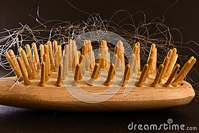 Wooden hairbrush with blonde hairs in it, black background Stock Photo