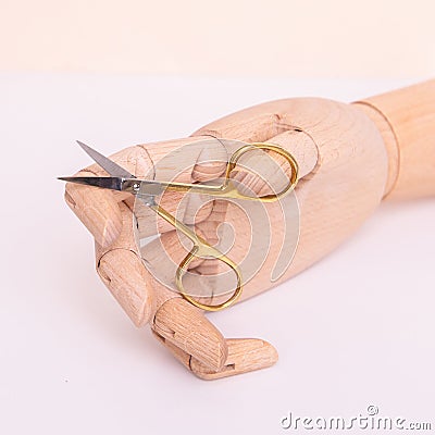 Wooden hand holding scissors for cutting nail Stock Photo