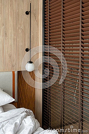 Wooden headboard with lamp and blinds in bedroom Stock Photo