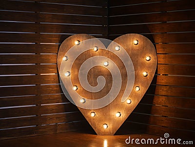 Wooden heart with light bulbs on the contour on the background of wooden boards. in the studio. horizontally Stock Photo