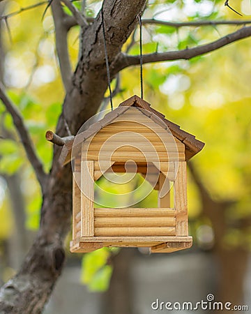 Wooden homemade house hanging on a tree, bird feeder. Small log house for feeding small birds in winter Stock Photo