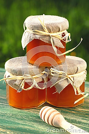 Wooden honey dipper and jars full of delicious fresh honey in apiary Stock Photo