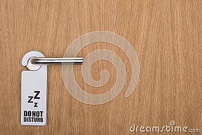 Wooden hotel room door with do no disturb sign on handle Stock Photo