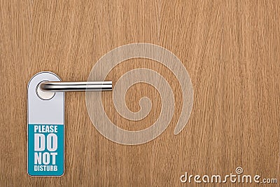 Wooden hotel room door with please do no disturb sign on handle Stock Photo