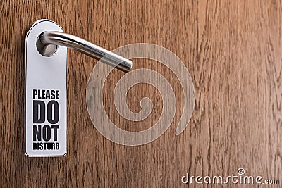 Wooden hotel room door with please do no disturb sign on handle Stock Photo