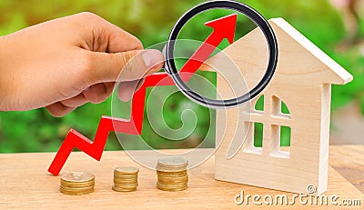 wooden house with a coins and red arrow up. concept of high demand for real estate. rise in house prices. population growth. Stock Photo