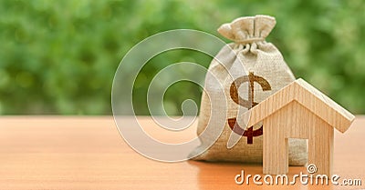 Wooden house figurine and money bag with a dollar symbol. Budget, subsidized funds. Mortgage loan for purchase housing Stock Photo