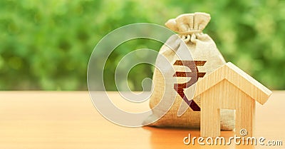 Wooden house figurine and money bag with indian rupee INR symbol. Budget, subsidized funds. Mortgage loan for purchase housing, Stock Photo