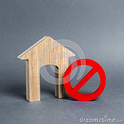 Wooden house figurine and a red prohibition symbol NO. Concept of inaccessibility or lack of housing. There is no opportunity Stock Photo