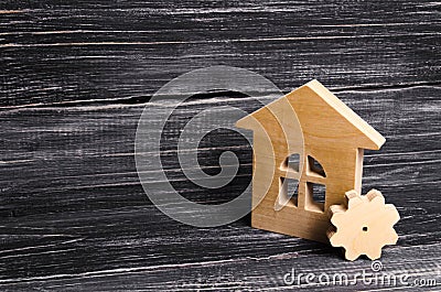 Wooden house with a gear on a background of dark wood. The concept of the enterprise for production, manufactory. Repair Stock Photo