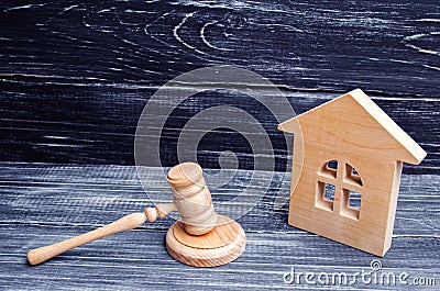 Wooden house and a hammer of the judge on a black background. Court cases on property and real estate. Confiscation and nationaliz Stock Photo