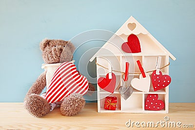 Wooden house with many hearts and cute teddy bear Stock Photo