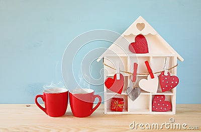 Wooden house with many hearts next to coffee cups Stock Photo