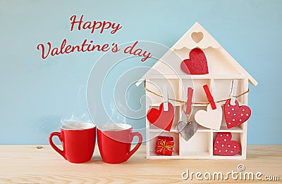 Wooden house with many hearts next to coffee cups Stock Photo