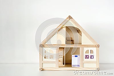 Wooden house model with 500 euro bill. House rental and sale. Expenses and costs for house handling. Housing savings concept.Copys Stock Photo