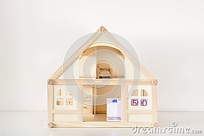 Wooden house model with 500 euro bill. House rental and sale. Expenses and costs for house handling. Housing savings concept.Copys Stock Photo