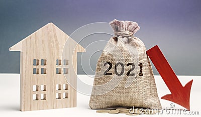 Wooden house and 2021 money bag with down arrow. Forecasting the real estate market concept. Interest rates falling. Investment, Stock Photo