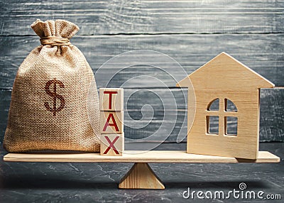 Wooden house and a money bag with the word Tax on the scales. Taxes on real estate, payment. Register of taxpayers for property. Stock Photo