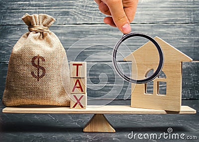 Wooden house and a money bag with the word Tax on the scales. Taxes on real estate, payment. Register of taxpayers for property. Stock Photo